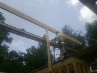 Carpenter setting a ridge beam over a new addition frame — Ice Dam Removal by Roofing Brothers in Hartsel