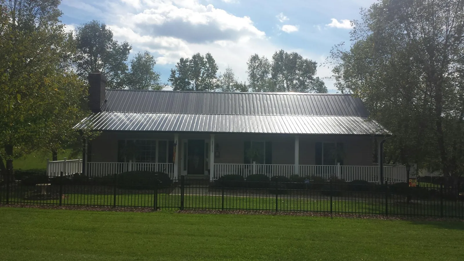 Gray metal roof on a brick ranch with a full width front porch — Gutter Guard Installation work by our crew in Hartsel