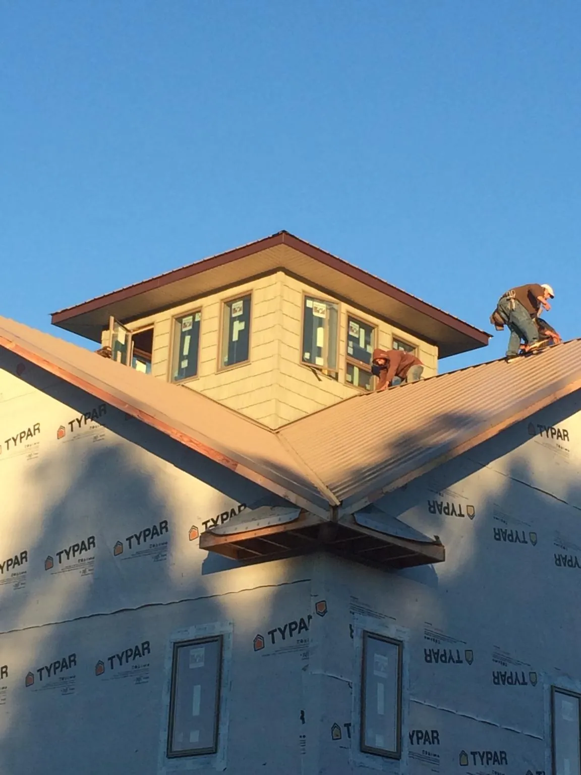 Roofers working around a rooftop cupola on a new metal roof at sunset — Roof Waterproofing in Hartsel by Roofing Brothers